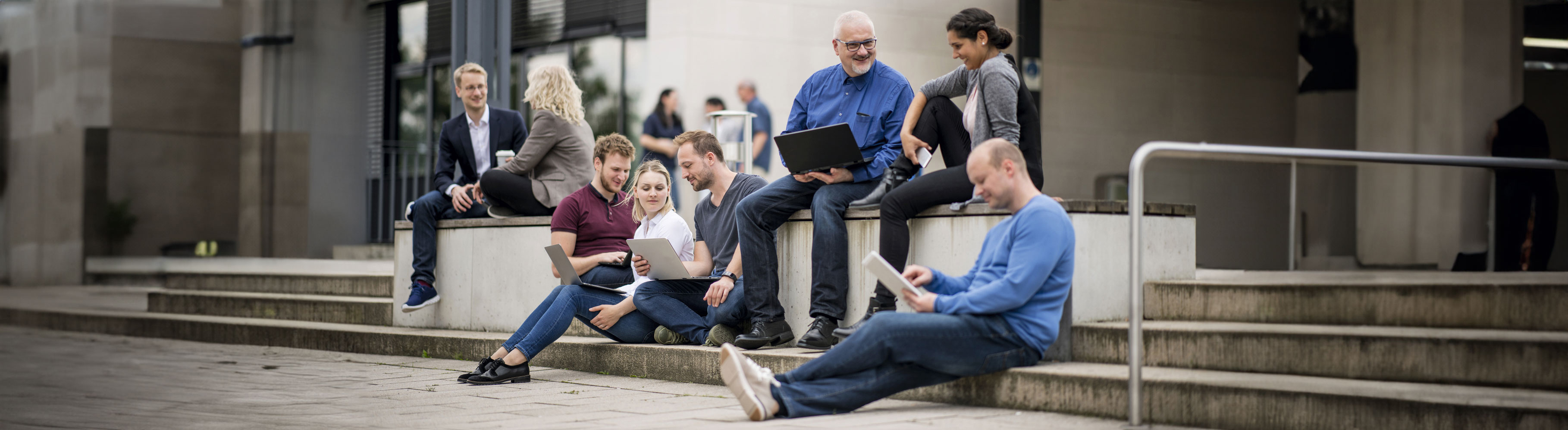 Titelbild: Studierende sitzen auf dem Campus